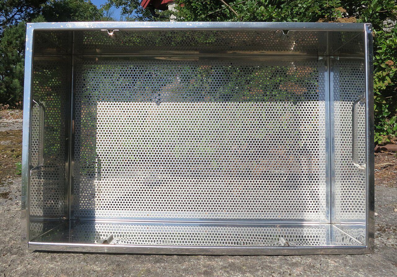 Perforated stainless steel inner basket of an uncapping tray