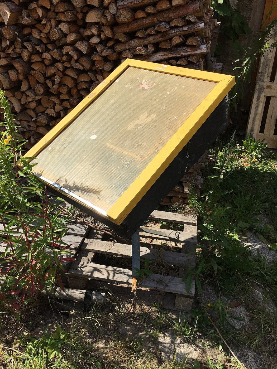 Glass-topped solar wax melter facing the sun outdoors