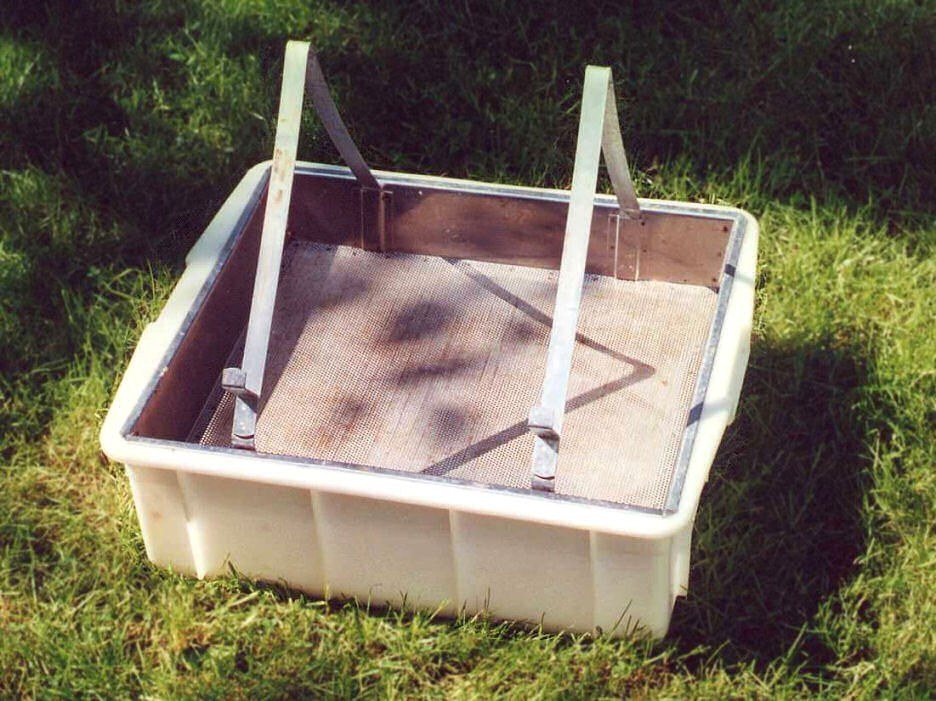 Plastic uncapping tray with a metal frame rest
