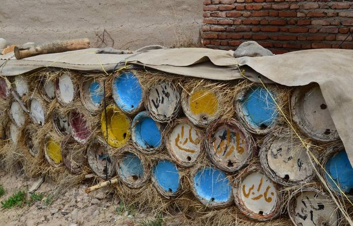 Tonbeuten mit bunten Deckeln vor einer Mauer im Iran